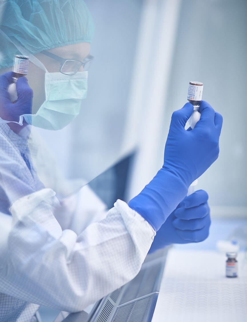 Laborant in Schutzkleidung hält Impfstofffläschchen in einem kontrollierten Umfeld.